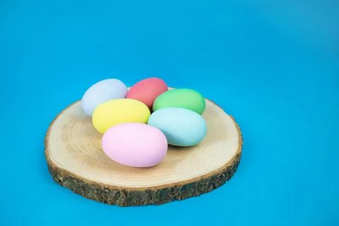 Easter, plain, multi-colored eggs on a hemp plate on a blue background Stock Photos