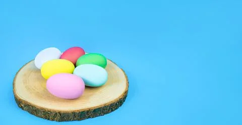 Easter, plain, multi-colored eggs on a hemp plate on a blue background. Banner Stock Photos