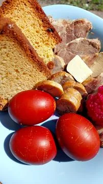 Easter plate featuring decorated eggs, bread, meats, and traditional accomp.. Stock Photos