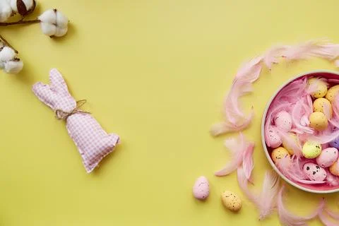 Easter post card concept. Pink bowl with colorful eggs, pink feathers and Stock Photos