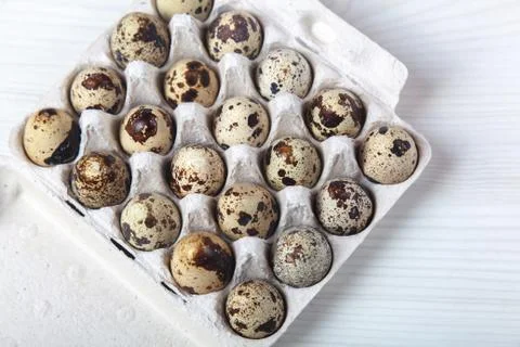 Easter quail eggs in container on bright background 库存照片