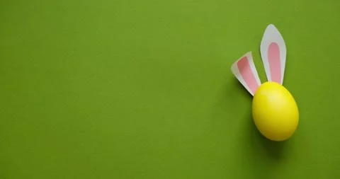 Easter rabbit ears on a yellow egg on a green background with a place for text Stock Footage 235770024