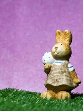 Easter rabbit hold easter eggs on the green grass the background is royal pur Stock Photos