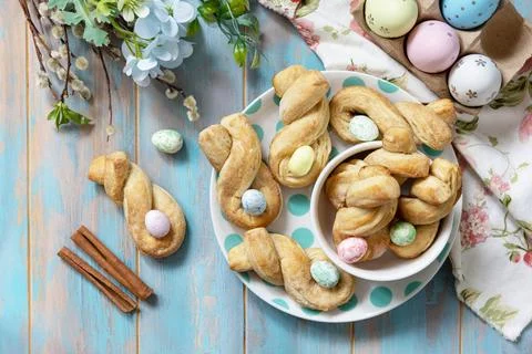 Easter rabbit-shaped buns puff pastry with  cinnamon on a wooden blue table.. Stock Photos