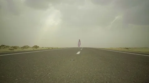Easter rabbit walks, jumps on middle of asphalt road in desert. Man in pink Stock Footage 80066844