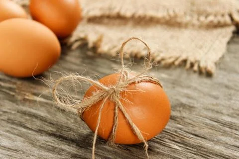 Easter. Raw eggs in the bow on sackcloth on wooden table Stock Photos