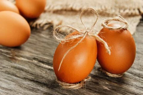 Easter. Raw eggs in the bow on sackcloth on wooden table Stock-Fotos