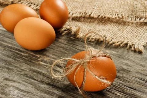 Easter. Raw eggs in the bow on sackcloth on wooden table Stock Photos