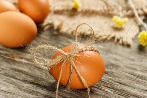 Easter. Raw eggs in the bow on sackcloth on wooden table Stock Photos