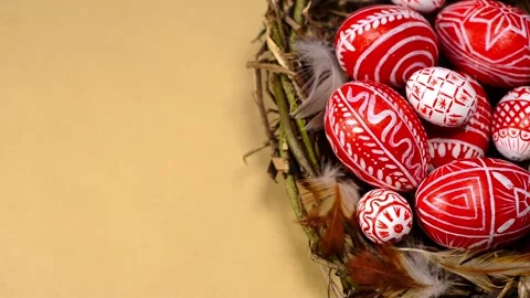 Easter red eggs with folk pattern inside nest. Man rotate one egg on paper Stock-Footage 127887731