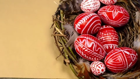 Easter red eggs with folk pattern into bird nest. Man's hand add eggs to nest. Stock-Footage 127887762