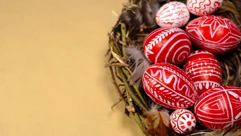 Easter red eggs with folk pattern into bird nest on paper. Man's hand add eggs Stock-Footage 127887797