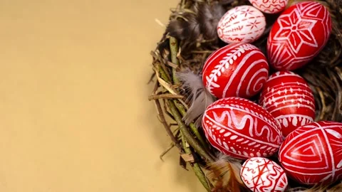 Easter red eggs with folk pattern into bird nest on paper. Man's hand add eggs Stock-Footage 127887826