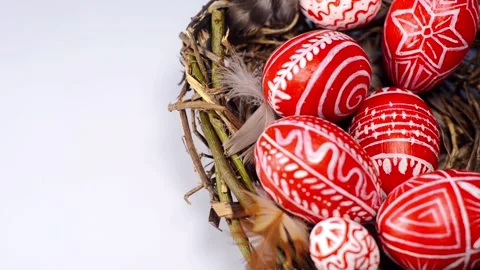 Easter red eggs with folk pattern into bird nest on white. Hand add eggs to nest Video stock 127887888