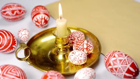 Easter red eggs with folk pattern lay on candlestick with burning candle stand Stock-Footage 127888612