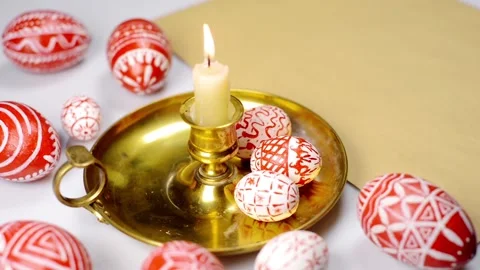 Easter red eggs with folk pattern lay on candlestick. Hand rotate one eggs Stock-Footage 127888629