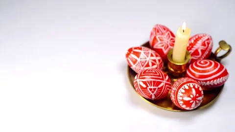 Easter red eggs with folk white pattern lay on brass candlestick on white Stock-Footage 127886807