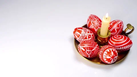 Easter red eggs with folk white pattern lay on brass candlestick on white Video stock 127886839