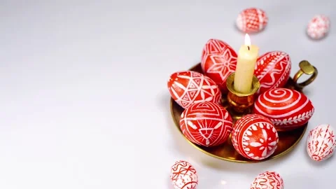 Easter red eggs with folk white pattern lay on brass candlestick on white Stock-Footage 127886892
