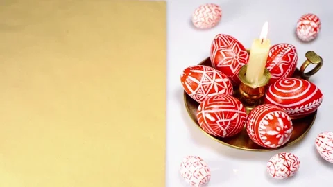 Easter red eggs with folk white pattern lay around brass candlestick Stock Footage 127886972