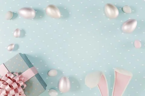 Easter scene with pastel eggs, a gift box, and bunny ears Stock Photos