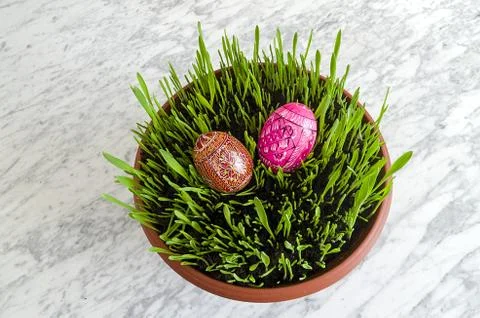 Easter seedlings with colorful easter eggs on a marble table Stock Photos