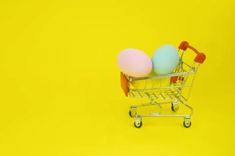 Easter . Shopping cart with Easter eggs on a yellow background Stock Photos