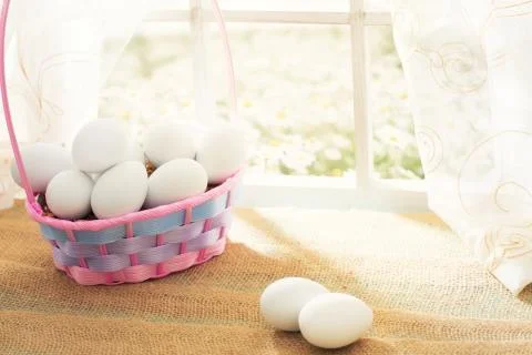 Easter shopping theme: white eggs in a basket on the window in a sunny day 스톡 사진