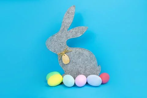 Easter, soft, gray hare and eggs are plain, multi-colored on a blue background. Stock Photos