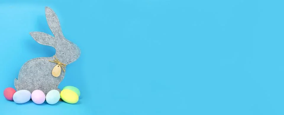 Easter, soft, gray hare and eggs are plain, multi-colored on a blue background. Stock Photos