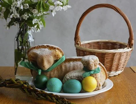 Easter still life containing two lamb cakes, painted eggs and a wicker basket Stock Photos