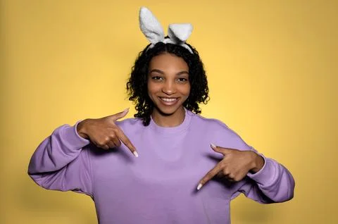 Easter studio shot with cute young woman in easter bunny ears pointing at empty 写真素材