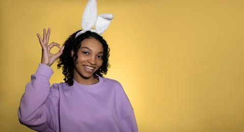 Easter studio shot with cute young woman in easter bunny ears showing ok sign Foto stock