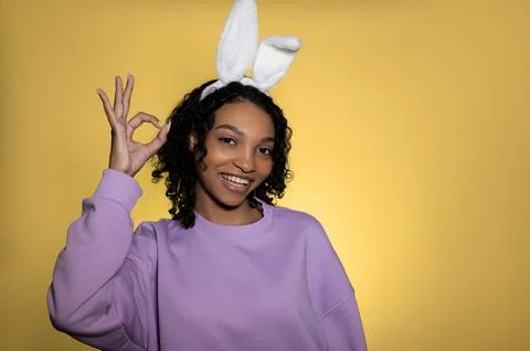 Easter studio shot with cute young woman in easter bunny ears showing ok sign Stock Photos