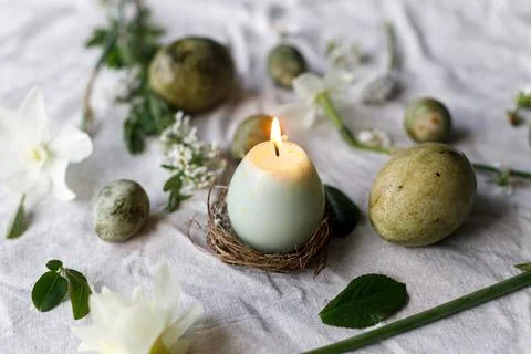 Easter. Stylish easter eggs, candle, flowers and cherry blossoms on linen clo Stock Photos