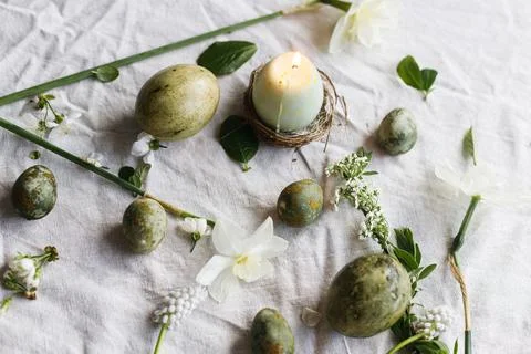 Easter. Stylish easter eggs, candle, flowers and cherry blossoms on linen clo Stock Photos