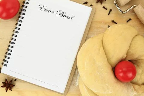 Easter sweet bread dough with red egg and recipe book on the table Stock Photos