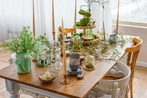 Easter table decor with candles, greenery and bunny figurines in bright spr.. Stock Photos