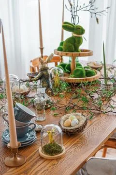 Easter table decor with candles, greenery and bunny figurines in bright spr.. Stock Photos