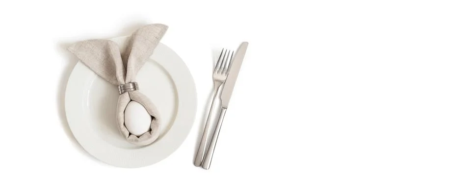 Easter table decorations with egg in a gray Easter bunny napkin on a white Stock Photos