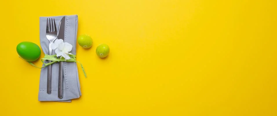 Easter table, place setting. Easter eggs, green color painted, cutlery and gr Stock Photos