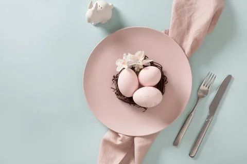 Easter table setting background with pink plate, eggs and bunny. Stock Photos
