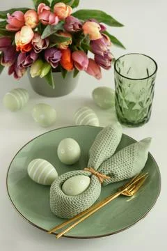 Easter Table Setting with Bunny Napkin, Decorated Eggs and Colorful Tulips... Stock Photos