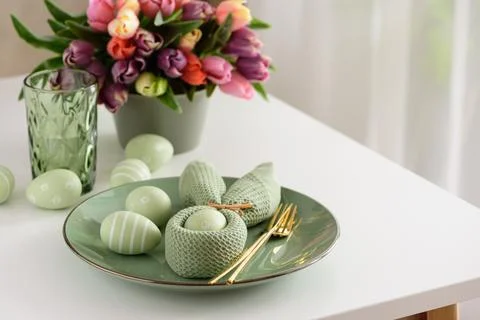 Easter Table Setting with Bunny Napkin, Decorated Eggs and Colorful Tulips... Stock Photos