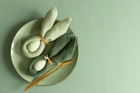 Easter Table Setting with Bunny Napkins Decorated Eggs on Green Background... Stock Photos