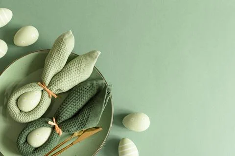 Easter Table Setting with Bunny Napkins Decorated Eggs on Green Background... Stock Photos