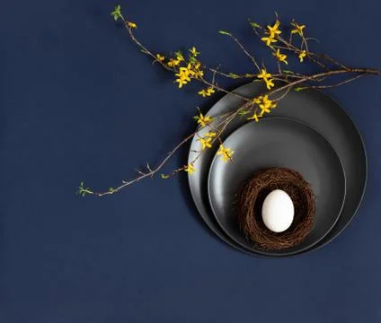 Easter table setting with a chicken egg in a nest on black plates  Stock Photos
