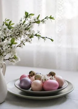 Easter table setting with colorful pastel Easter eggs on a gray plate and che Stock Photos