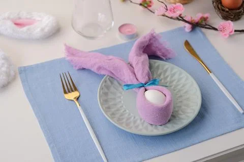 Easter table setting, egg with bunny ears on plate on table decorated for E.. Stock Photos