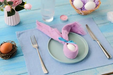 Easter table setting, egg with bunny ears on plate on table decorated for E.. Stock Photos